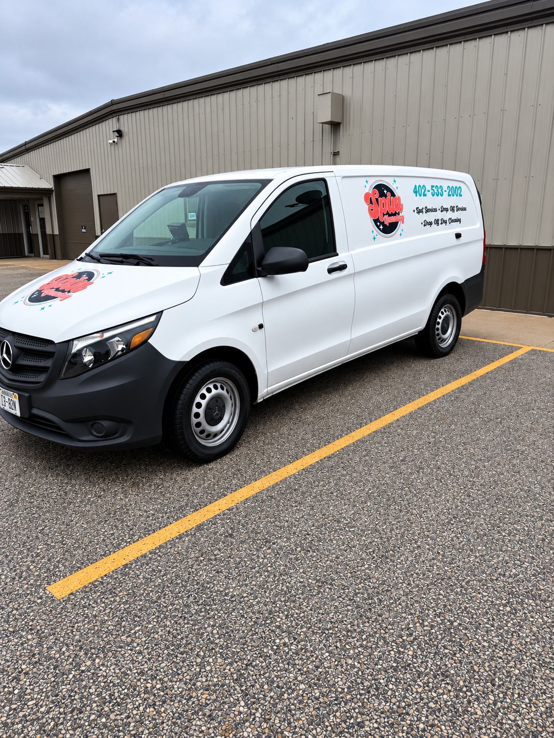 The white Spin Laundry pickup and delivery van with the Spin Laundry logo and phone number on the side